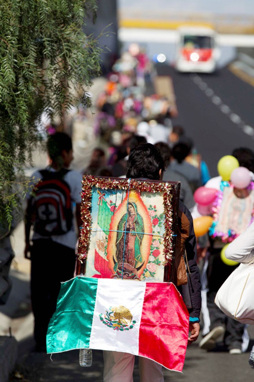 A pilgrim carries a statue of the Virgin of Guadalupe on his back as he makes his way with other pilgrims toward the Basilica of Guadalupe along a highway entering Mexico City. (AP Photo/Eduardo Verdugo)