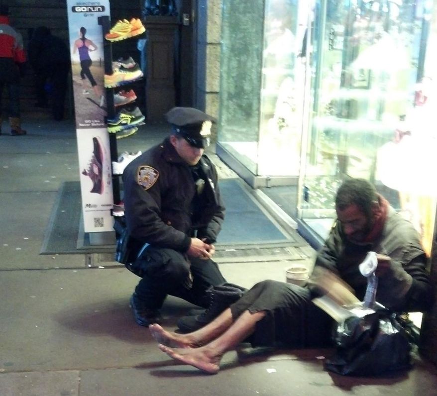 ** FILE ** This file photo provided by Jennifer Foster from Nov. 14, 2012, shows New York City Police Officer Larry DePrimo presenting a barefoot homeless man in New York's Time Square with boots. (AP Photo/Jennifer Foster, File)