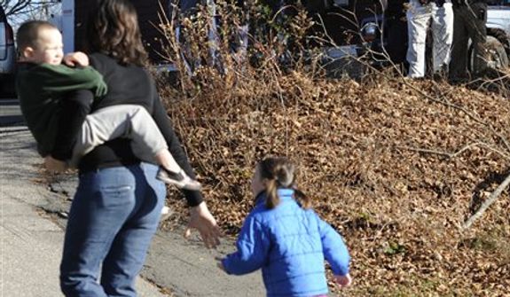 A mother runs with her children as police above canvass homes in the area following a shooting at the Sandy Hook Elementary School in Newtown, Conn., about 60 miles (96 kilometers) northeast of New York City, Friday, Dec. 14, 2012. An official with knowledge of Friday's shooting said 27 people were dead, including 18 children. (AP Photo/Jessica Hill)