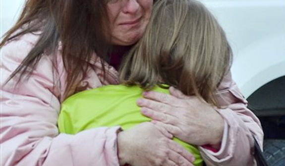 A mother hugs her daughter following the shootings at the Sandy Hook Elementary School in Newtown, Conn., about 60 miles northeast of New York City, on Friday, Dec. 14, 2012. (AP Photo/The New Haven Register, Melanie Stengel)