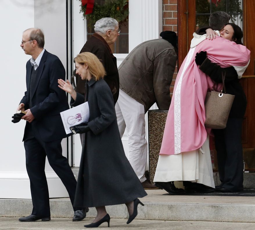 A priest embraces a woman outside St. Rose of Lima Roman Catholic Church between Masses on Sunday, Dec. 16, 2012, in Newtown, Conn. (AP Photo/Julio Cortez)