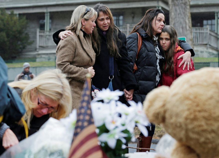 Women embrace at the site of a makeshift memorial for school shooting victims at the village of Sandy Hook in Newtown, Conn., Sunday, Dec. 16, 2012. (AP Photo/Charles Krupa)