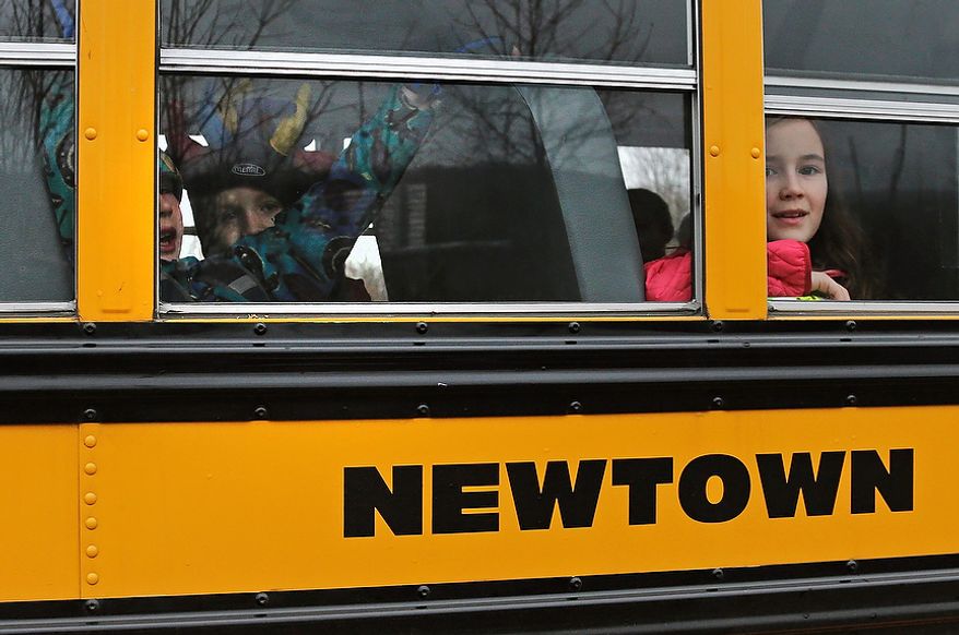 **FILE** Schoolchildren look out the window of their bus as they head back to school in Newtown, Conn., on Dec. 18, 2012. Classes resume Tuesday for Newtown schools except those at Sandy Hook. Buses ferrying students to schools were festooned with large green and white ribbons on the front grills, the colors of Sandy Hook. At Newtown High School, students in sweatshirts and jackets, many wearing headphones, betrayed mixed emotions. Adam Lanza walked into Sandy Hook Elementary School in Newtown, Friday and opened fire, killing 26 people, including 20 children, before killing himself. (AP Photo/Charles Krupa)