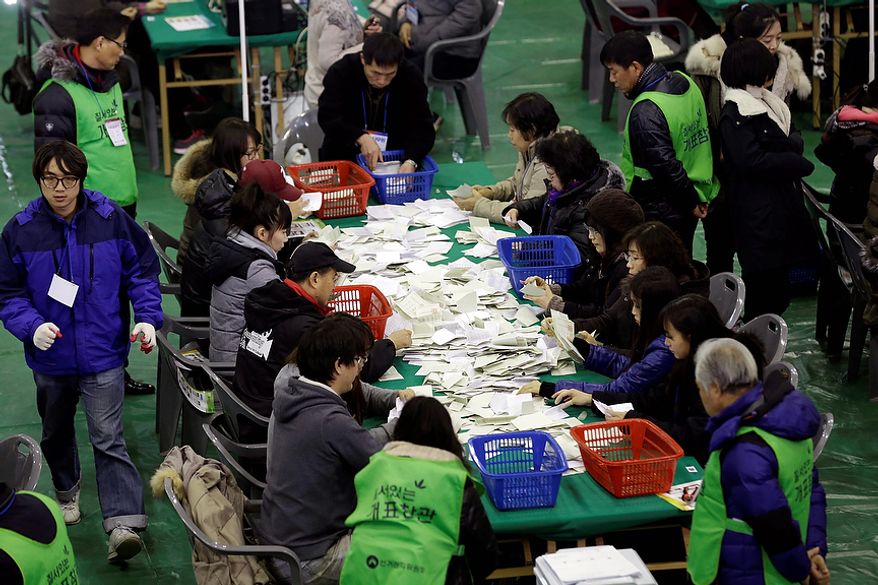 South Korean National Election Commission officials sort out ballots cast in the country's presidential election as they begin the counting process in Seoul on Wednesday, Dec. 19, 2012. South Koreans voting for president Wednesday were almost evenly divided between the conservative daughter of a late dictator and the liberal son of North Korean refugees, according to surveys released after the polls closed. (AP Photo/Lee Jin-man)
