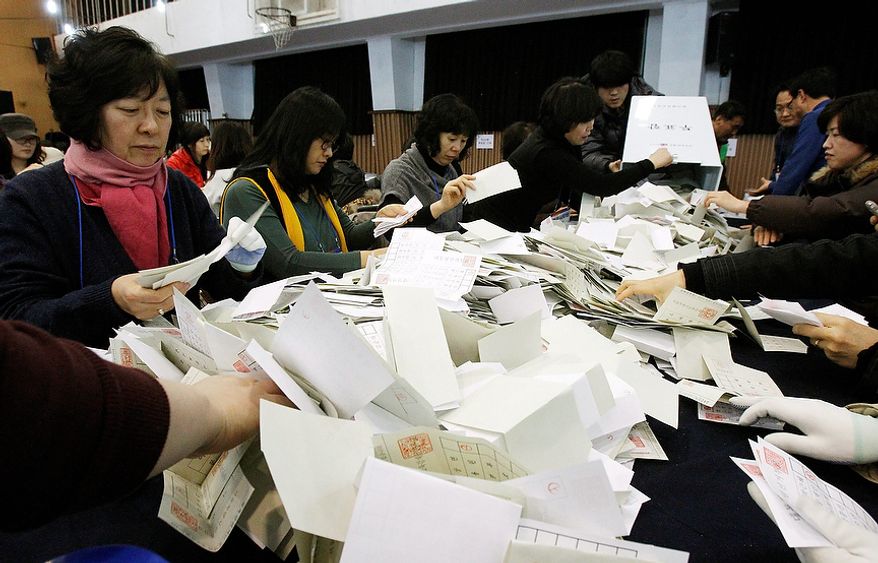 South Korean National Election Commission officials sort out ballots cast in the presidential election as they begin the counting process in Seoul on Wednesday, Dec. 19, 2012. South Koreans voting for president Wednesday were almost evenly divided between the conservative daughter of a late dictator and the liberal son of North Korean refugees, according to surveys released after the polls closed. (AP Photo/Ahn Young-joon)