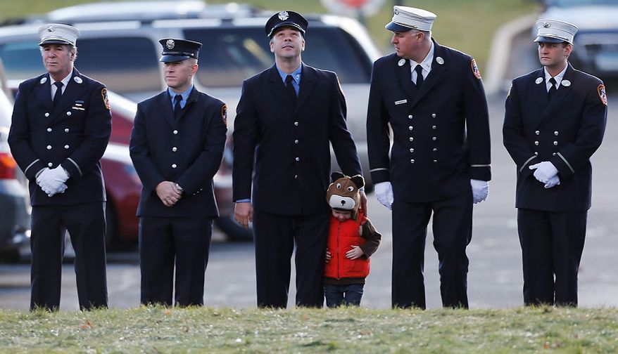 A child lines up with firefighters outside the funeral for school shooting victim Daniel Gerard Barden,at St. Rose of Lima Catholic Church in Newtown, Conn., Wednesday, Dec. 19, 2012. According to firefighters, Daniel wanted to be a firefighter when he grew up and they honored him at the service. Gunman Adam Lanza opened fire killing 26 people, including 20 children, at Sandy Hook Elementary School in Newtown before killing himself on Friday. (AP Photo/Charles Krupa)