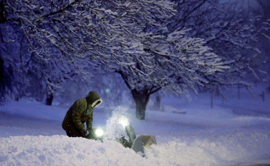 A man clears snow from his driveway after a snowfall left many schools and businesses closed for the day in Urbandale, Iowa, on Thursday. Forecasters warned of blizzard conditions for commuters from Kansas to Wisconsin. (Associated Press)
