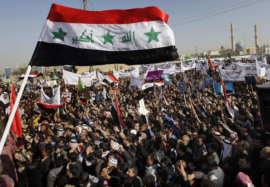 ** FILE ** Protesters chant slogans against Iraq's Shiite-led government as they wave national flags and hold posters of Sunni Finance Minister Rafia al-Issawi during a demonstration in Fallujah, 40 miles west of Baghdad, on Sunday, Dec. 23, 2012. Thousands protested in Iraq's western Sunni heartland following the arrest of bodyguards assigned to the finance minister, who draws support from the area. The Khulafa al-Rashideen Mosque is seen at right. (AP Photo/Khalid Mohammed)