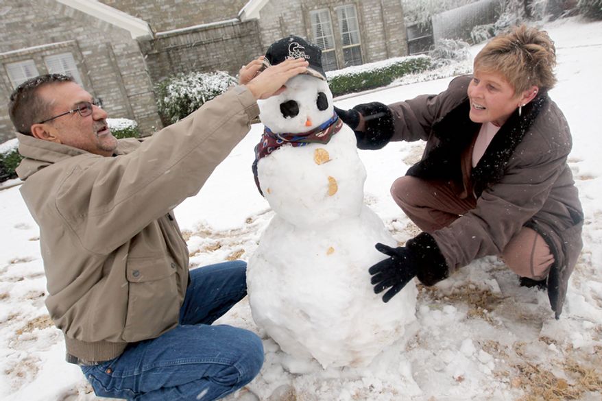Tommy and Cindy Huddleston put the finishing touches on their snowman in Paris, Texas Tuesday, Dec. 25, 2012 after a strong winter system dropped inches of rain and snow on most of North East Texas. (AP Photo/The Paris News, Sam Craft)