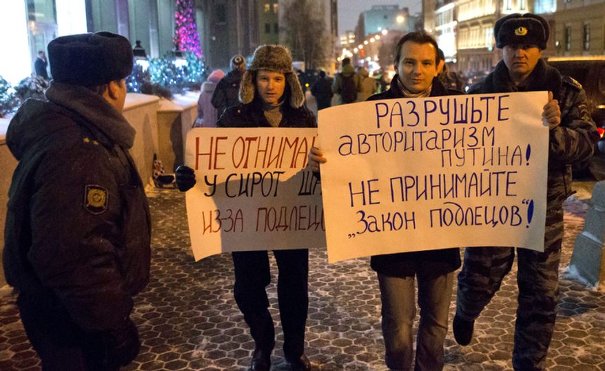 Russian police officers detain demonstrators protesting outside the Russian parliament's upper chamber in Moscow on Dec. 26, 2012, against a bill banning U.S. adoptions of Russian children. (Associated Press)