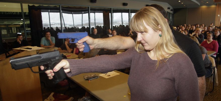 Clark Aposhian (rear), president of Utah Shooting Sport Council, demonstrates with a plastic gun while Joanna Baginska, a fourth-grade teacher at Odyssey Charted School in American Fork, uses a 40 cal. Sig Sauer on Dec. 27, 2012, during concealed-weapons training for 200 Utah teachers in West Valley City, Utah. The Utah Shooting Sports Council offered six hours of training in handling concealed weapons in the latest effort to arm teachers to confront school assailants. (Associated Press)