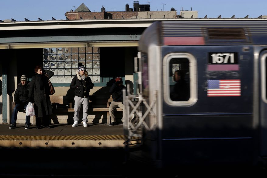 Commuters watch as a train enters the 40th Street-Lowry Street Station, where a man was killed after being pushed onto the subway tracks, in the Queens borough of New York on Friday, Dec. 28, 2012. (AP Photo/Seth Wenig)