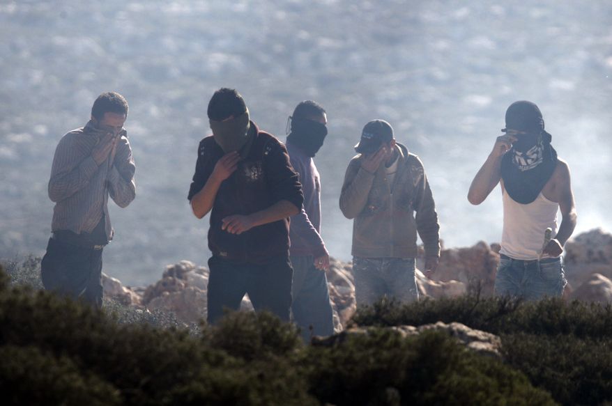 Palestinians protesters react to tear gas shot by Israeli soldiers during clashes near the West Bank village of Qusra, near Nablus, on Tuesday, Jan. 1, 2013. (AP Photo/Nasser Ishtayeh)