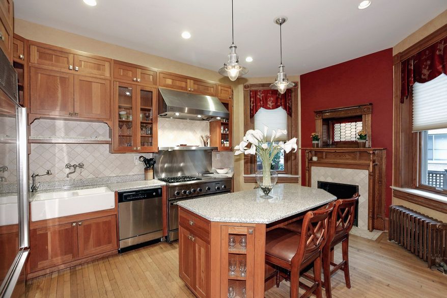 The kitchen has granite counters, stainless steel appliances and a large center island with room for seating. A fireplace is tucked underneath a stained-glass window and is flanked by two more tall windows.