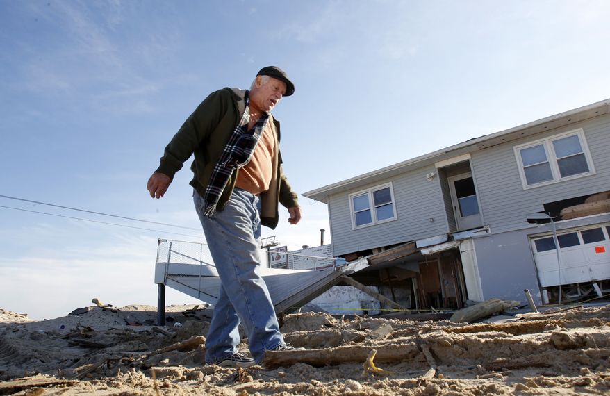 Henny Mauro walks in Seaside Heights, N.J., on Jan. 3, 2013, past a beach-side home that was destroyed by Superstorm Sandy. (Associated Press)