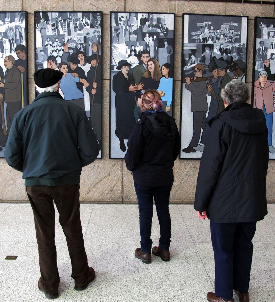 Richard and Pat Bamforth and their grand- daughter Pippa Adam look at the mural depicting Maine's labor history on its return to public display Monday in the capital. (Associated Press)