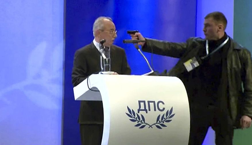 Image grab from video shows a man identified as Oktai Enimehmedov, 25, as he points a weapon at Ahmed Dogan, left, leader of the Movement for Rights and Freedoms, during his speech at his party's congress in Sofia, on Saturday, Jan. 19, 2013. Dogan struck the man before other delegates wrestled the assailant to the ground, and no shots were fired. Police took the man away.(AP Photo/ BTVnews)