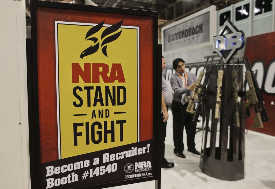 **FILE** A Diamondback Firearms representative (rear right) explains features of one of their rifles on display at the 35th annual SHOT Show in Las Vegas on Jan. 16, 2013. (Associated Press)