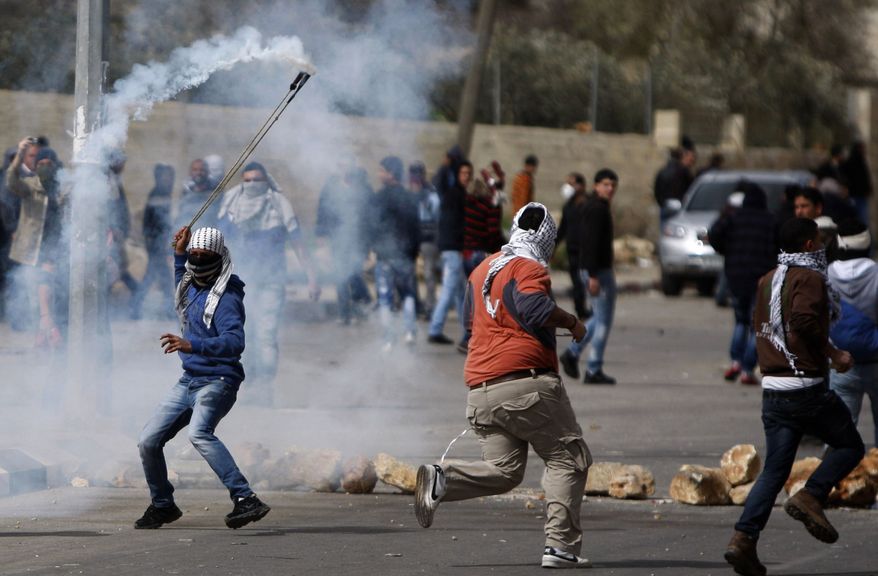 A masked Palestinian throws back a gas canister during a protest to support Palestinian prisoners, outside Ofer, an Israeli military prison near the West Bank city of Ramallah, Friday, Feb. 22, 2013. (AP Photo/Majdi Mohammed)
