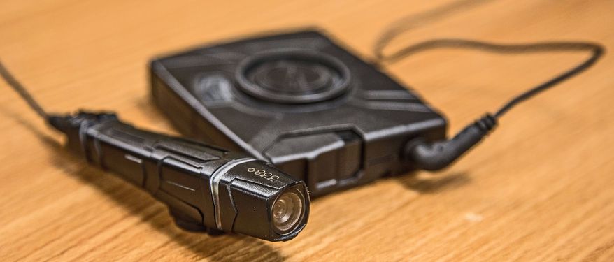 Laurel Police Deputy Chief James Brooks (right) helps Officer Carl Johnson in the proper way to wear a new Taser Axon Flex camera. Officer Matthew Jordan (left) is wearing one of the cameras. (Andrew S. Geraci/The Washington Times)