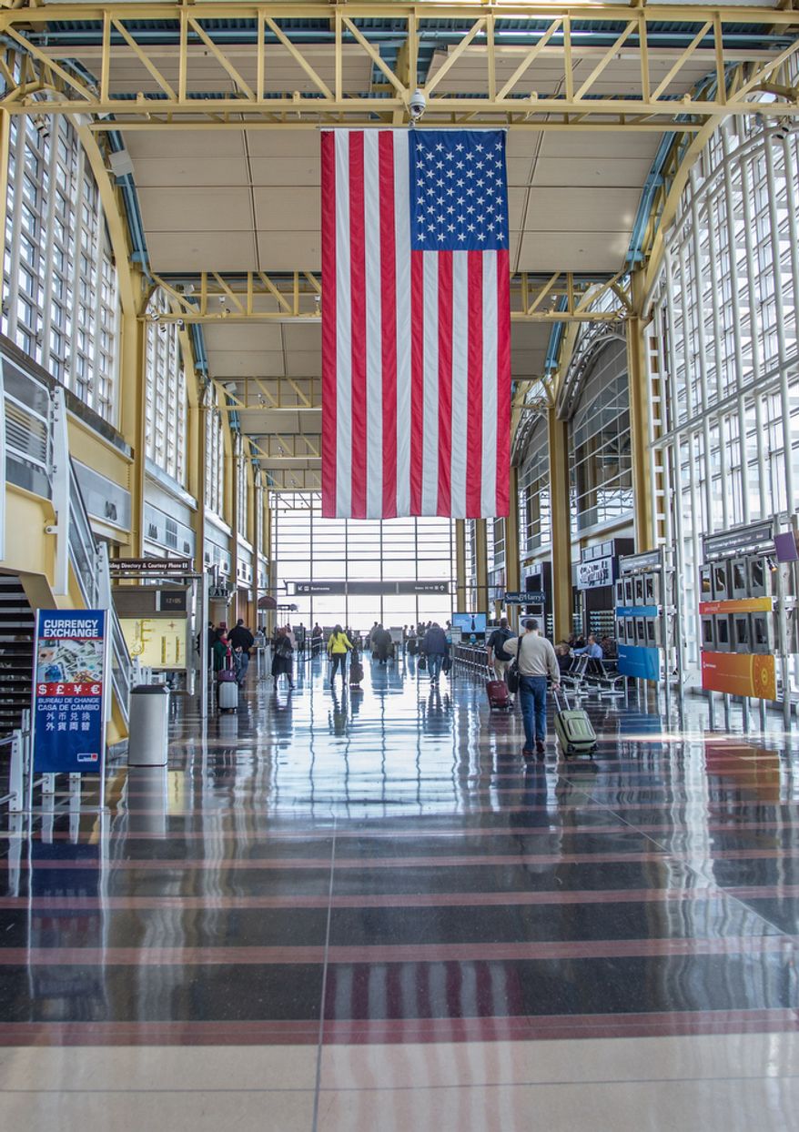 An U.S. flag hangs from the rafters at Reagan National Airport in Washington on Feb. 25, 2013, as travelers pass through. (Andrew S. Geraci/The Washington Times)