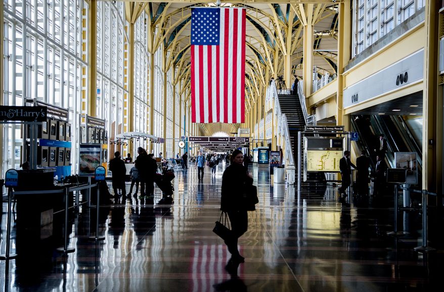 An U.S. flag hangs from the rafters at Reagan National Airport in Washington on Feb. 25, 2013, as travelers pass through. (Andrew S. Geraci/The Washington Times)