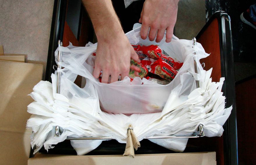 **FILE** A clerk bags groceries in plastic bags at the M Street Grocery in Seattle on Aug. 3, 2009. (Associated Press)