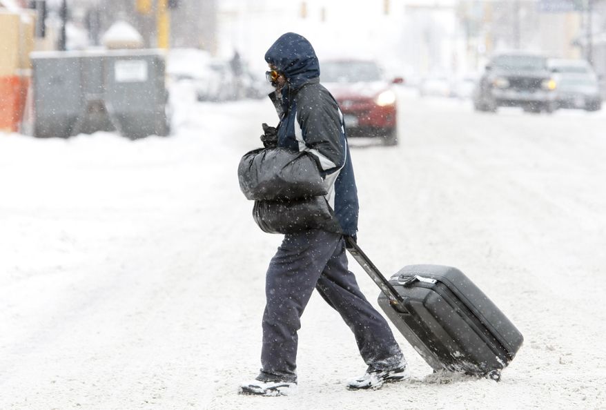 Maury Lawson drags his suitcase through the snow Monday, March 4, 2013, while crossing N.P. Avenue in Fargo, N.D., on his way to the bus depot. (AP Photo/Michael Vosburg, The Forum)