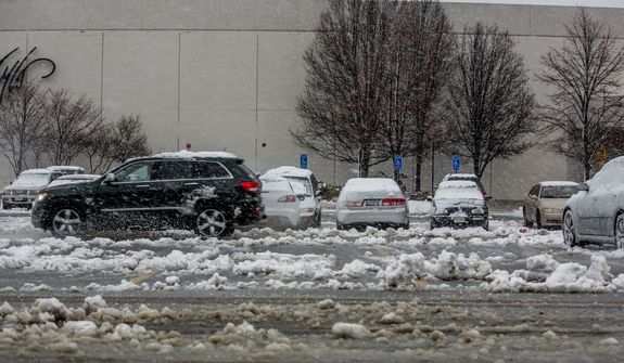 An SUV drives through the slushy parking lot of Fair Oaks Mall in Fairfax, Va., on March 6, 2013. (Andrew S. Geraci/The Washington Times)