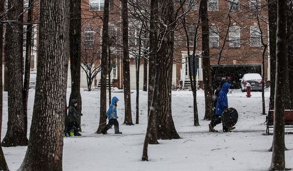Parents and children bundle up and hike through snow to find a hill to sled down in Fairfax, Va., on March 6, 2013. (Andrew S. Geraci/The Washington Times)