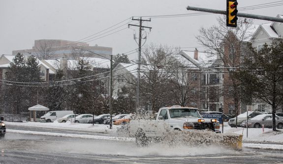 A truck uses its snowplow to remove slush from West Ox Road in Fairfax, Va., on March 6, 2013. (Andrew S. Geraci/The Washington Times)