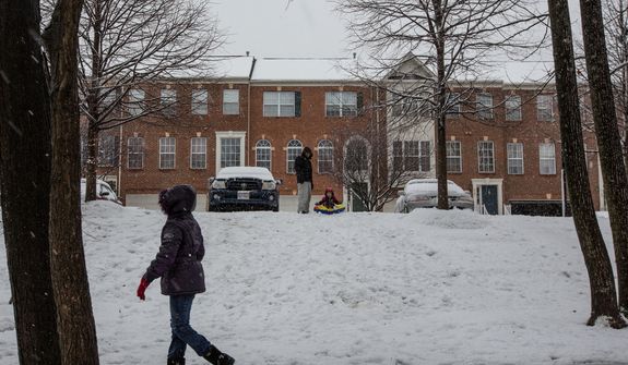Haeyong Lee and his son, Matthew, 2, prepare to sled down a hill while it snows in a neighborhood in Fairfax, Va., on March 6, 2013. (Andrew S. Geraci/The Washington Times)