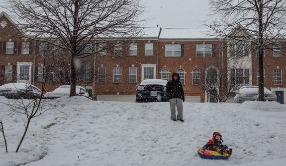 Haeyong Lee and his son, Matthew, 2, prepare to sled down a hill while it snows in a neighborhood in Fairfax, Va., on March 6, 2013. (Andrew S. Geraci/The Washington Times)