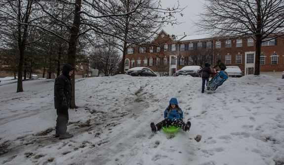 Children sled down a small hill while their parents watch in a neighborhood in Fairfax, Va., on March 6, 2013. (Andrew S. Geraci/The Washington Times)