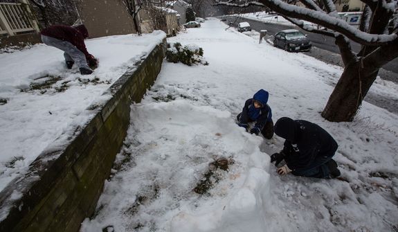 Mason Moy (left), 14, Calvin Crist (center), 13, and Sam Gustason, 13, build a snow fort in a front yard during a snow day in Fairfax, Va., on March 6, 2013. (Andrew S. Geraci/The Washington Times)