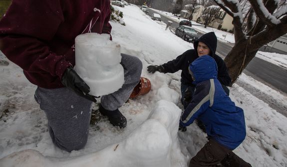 Mason Moy (left), 14, Sam Gustason (center), 13, and Calvin Crist, 13, build a snow fort in a front yard during a snow day in Fairfax, Va., on March 6, 2013. (Andrew S. Geraci/The Washington Times)