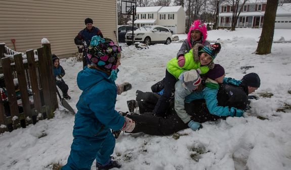 Members of the Sweeney and Powers families pile on top of Patrick Sweeney during a snowball fight in Fairfax, Va., on March 6, 2013. (Andrew S. Geraci/The Washington Times)