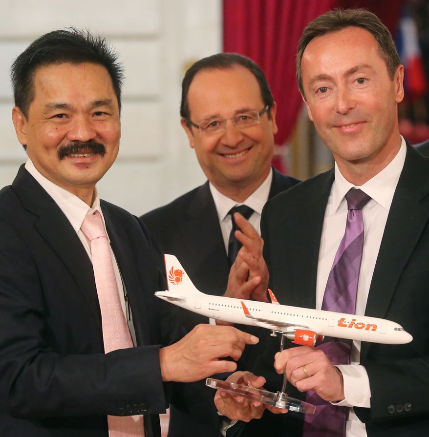 Rusdi Kirana (left), CEO of Lion Air, and Fabrice Bregier (right), CEO of Airbus, pose with an Airbus A320 model while French President Francois Hollande stands behind during a contract-signing ceremony at the Elysee Palace in Paris on Monday, March 18, 2013. Indonesian carrier Lion Air is to buy 234 short- to medium-range aircraft from Airbus for 18.4 billion euros ($24 billion) in what is being billed as the biggest civilian deal in the history of the aircraft manufacturer. (AP Photo/Michel Euler)