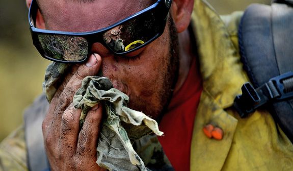 Vandenberg Air Force Base Hot Shot fire fighter Chris Loung wipes sweat from his face while cutting a fire line on June 28, 2012 in the Mount Saint Francois area of Colorado Springs, Co. while helping to battle several fires in Waldo Canyon. (U.S. Air Force photo by Tech. Sgt. Jeremy T. Lock)