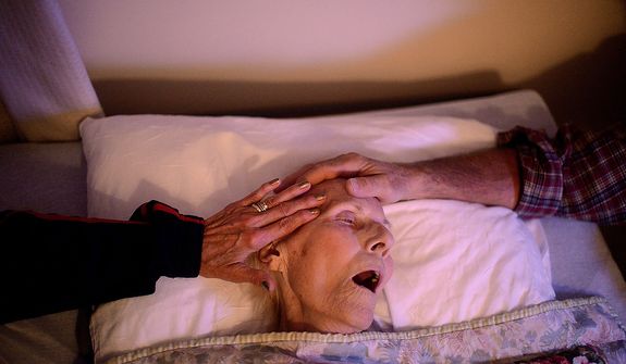 Son, USAF Lt. Col. (retired) Robert Lock and his wife Chris comfort his mother Mary as she takes her last couple of breaths in life on October 22, 2012 as she passes at a nursing facility in Gloversville, New York. Mary was 87 and placed in a nursing facility when she broke her femur over a year ago. (U.S. Air Force photo by Tech. Sgt. Jeremy T. Lock)
