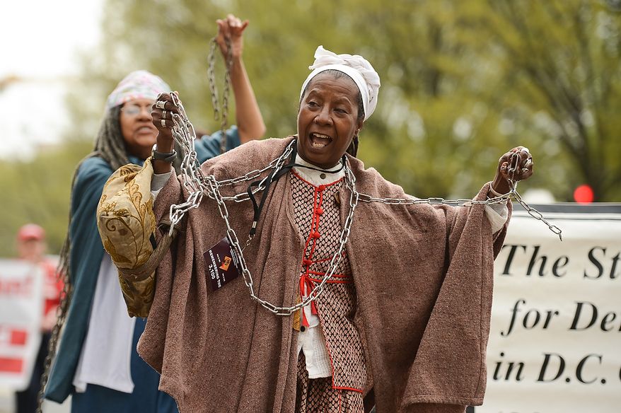 Ayo Handy-Kendi, center, and others wears chains to show their opposition to the district not having a voting representative in congress as she participates in the Washington, D.C. Emancipation Day parade, Washington, D.C., Tuesday, April 16, 2013. President Abraham Lincoln freed approximately 3,100 slaves in the District of Colombia on April 16, 1862, nine months before the Emancipation Proclamation. (Andrew Harnik/The Washington Times)