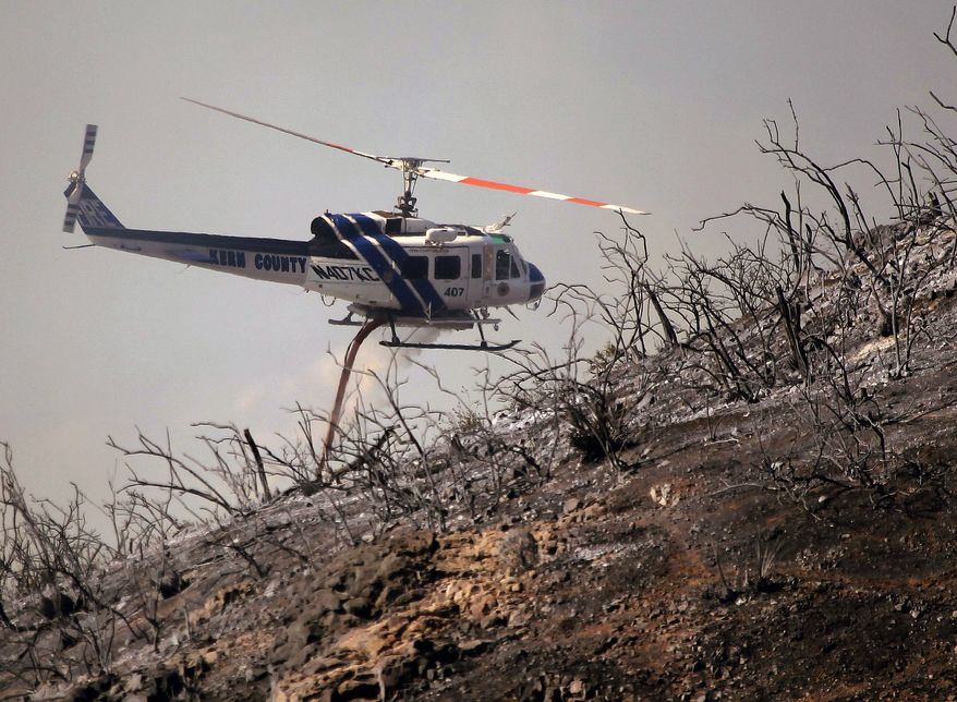 A Kern County Fire helicopter makes a water drop on a hotspot over a hill near Thousand Oaks, Calif. on Thursday, May 2, 2013. Authorities have ordered evacuations of a neighborhood and a university about 50 miles west of Los Angeles where a wildfire is raging close to subdivisions. The blaze on the fringes of Camarillo and Thousand Oaks broke out Thursday morning and was quickly spread by gusty Santa Ana winds. Evacuation orders include California State University, Channel Islands. (AP Photo/Nick Ut)