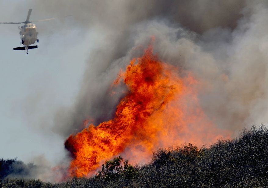 A helicopter makes a water drop on a hotspot over a hill near Thousand Oaks, Calif. on Thursday, May 2, 2013. Authorities have ordered evacuations of a neighborhood and a university about 50 miles west of Los Angeles where a wildfire is raging close to subdivisions. The blaze on the fringes of Camarillo and Thousand Oaks broke out Thursday morning and was quickly spread by gusty Santa Ana winds. Evacuation orders include California State University, Channel Islands. (AP Photo/Nick Ut)