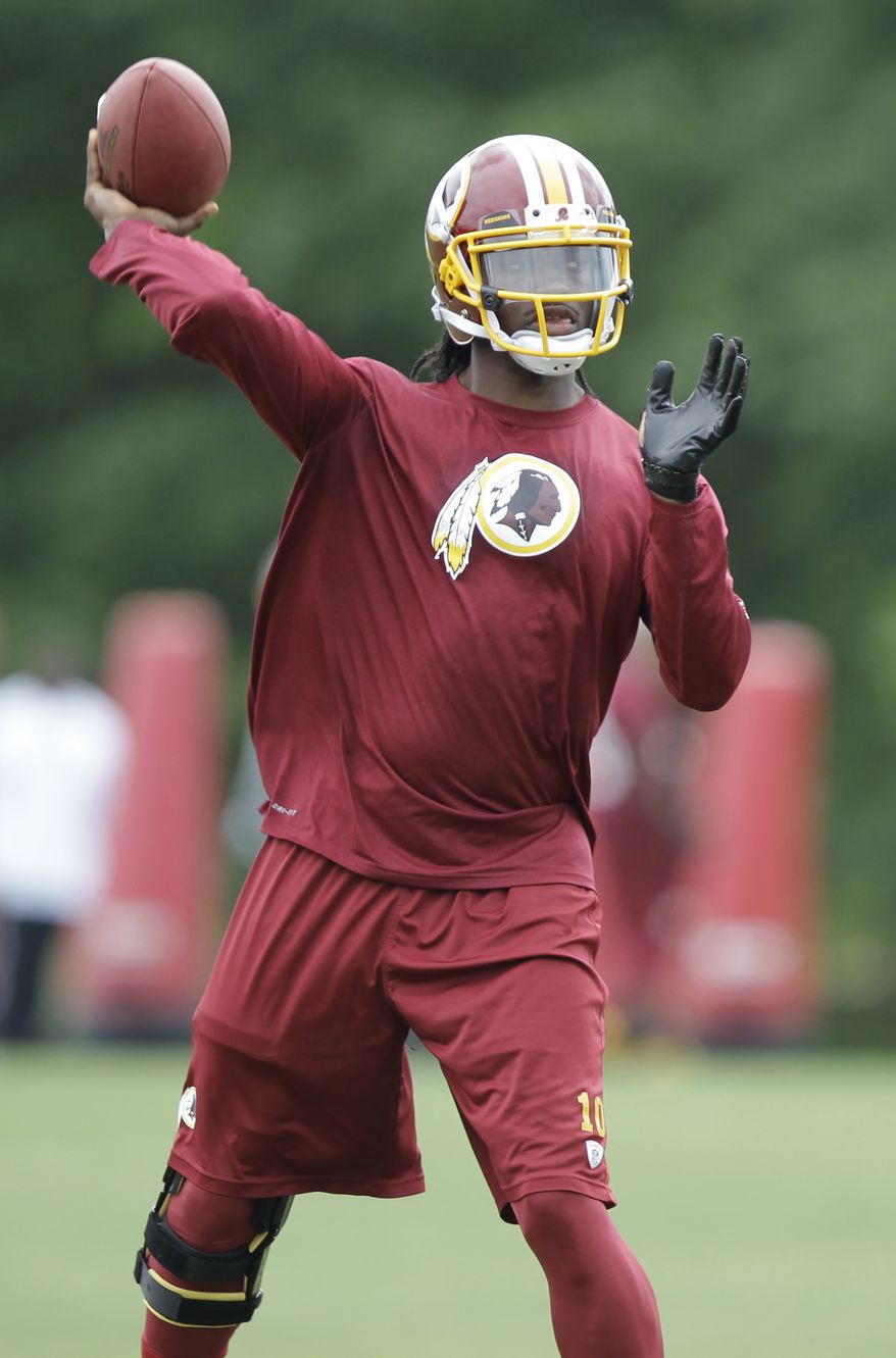 Washington Redskins quarterback Robert Griffin III throws a pass during team practice at Redskins Park, Thursday, June 6, 2013, in Ashburn, Va. (AP Photo/Luis M. Alvarez)
