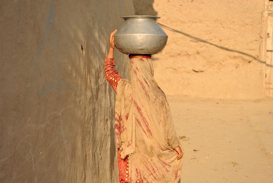 A woman returns home after fetching water in a village in Mohmand Agency (FATA). It is a woman’s task to collect and carry water for domestic use. Village houses usually do not have a direct water supply. Photo / Alamgir Khan