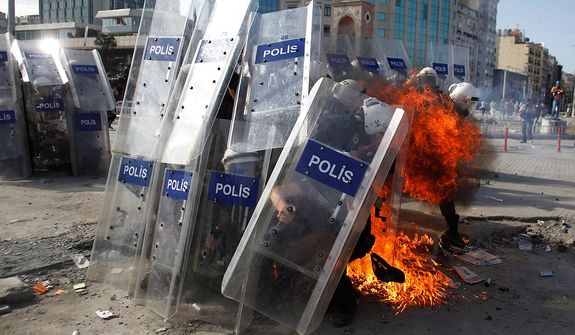 A gasoline bomb explodes in front of riot policemen during clashes in Taksim Square in Istanbul on Tuesday, June 11, 2013. Hundreds of police in riot gear forced through barricades and pushed many of the protesters who had occupied the square for more than a week into a nearby park. (AP Photo/Kostas Tsironis)