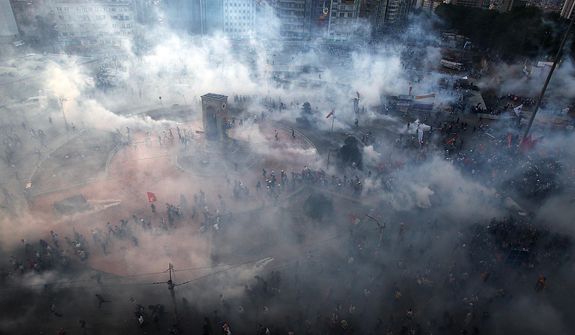 Protesters run to avoid tear gas during clashes at Taksim Square in Istanbul on Tuesday, June 11, 2013. Hundreds of riot police overran improvised barricades at the square and fired tear gas, rubber bullets and water cannon in running battles with protesters who have been occupying the area for more than a week. (AP Photo/Thanassis Stavrakis)
