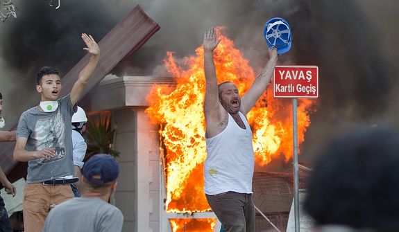 Protesters react during clashes in Taksim Square in Istanbul on Tuesday, June 11, 2013. Hundreds of police in riot gear forced through barricades and pushed many of the protesters who had occupied the square for more than a week into a nearby park. (AP Photo/Vadim Ghirda)