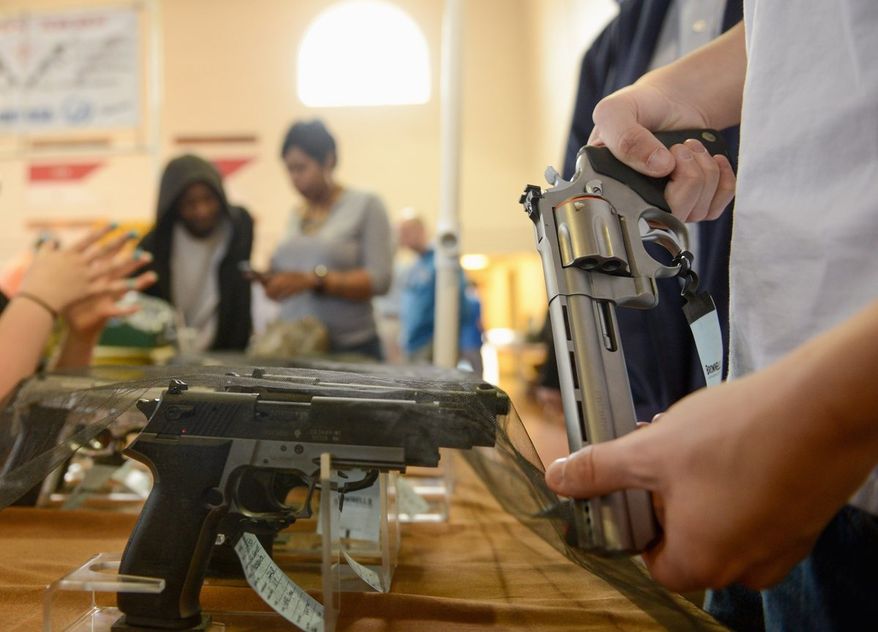 A man examines a handgun at the Annapolis Gun Show in March. June was the first month since October 2011 to see a year-over-year decrease in the total number of FBI instant background checks. (Andrew Harnik/The Washington Times)