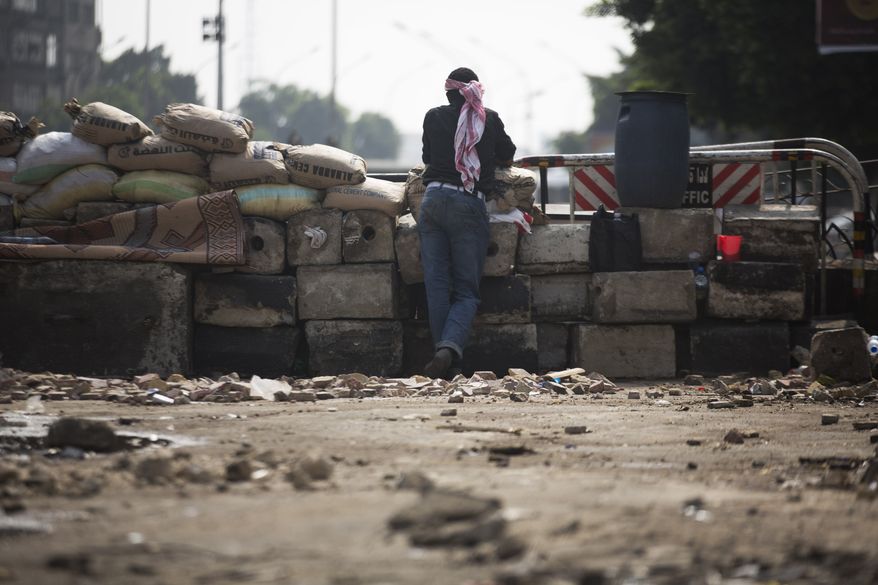 A supporter of ousted Egyptian President Mohammed Morsi stands guard at a barricade near Cairo University, where protesters have installed their camp, in Giza, Egypt, southwest of Cairo, on Sunday, July 7, 2013. (AP Photo/Manu Brabo)